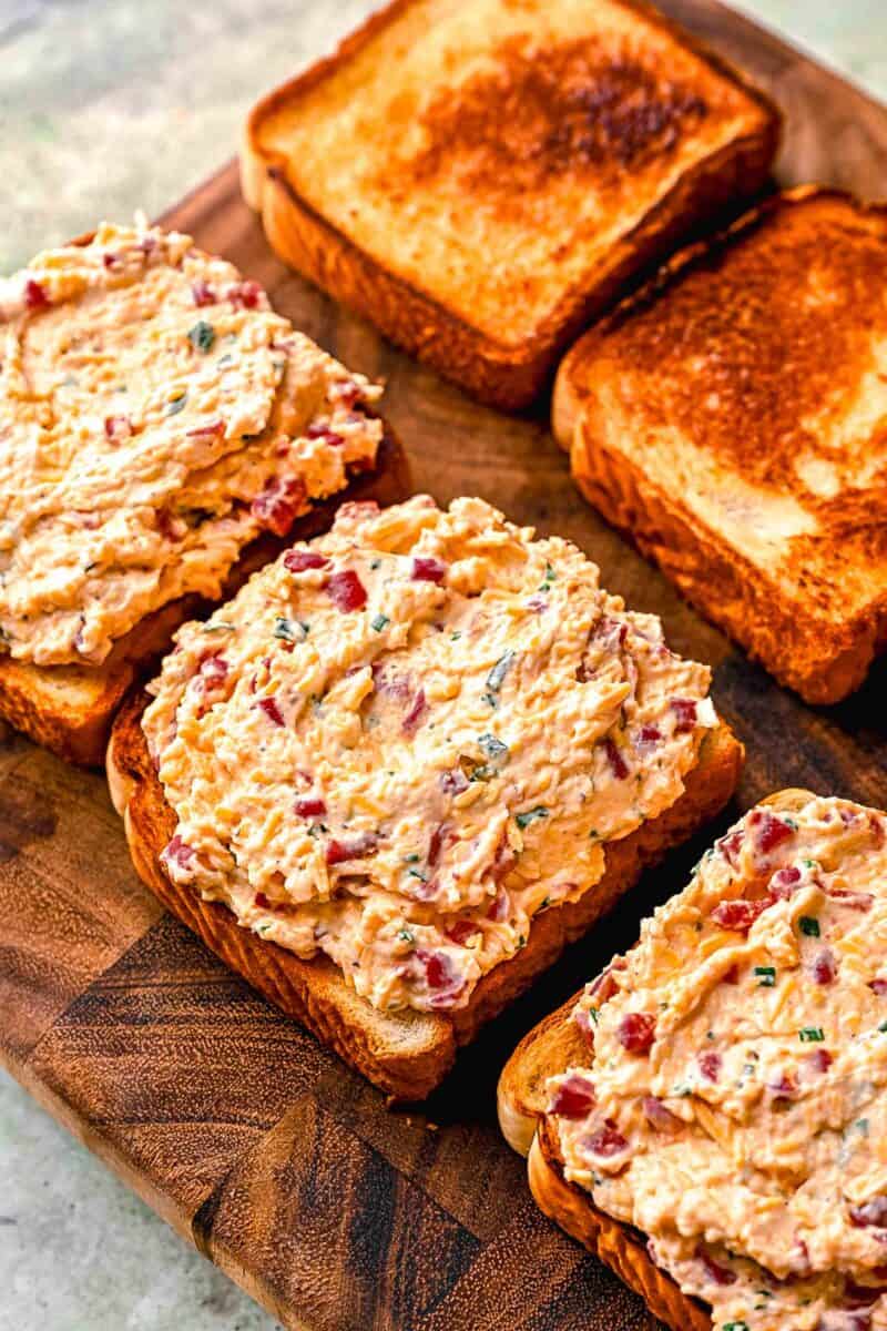 pimento cheese spread on slices of bread on a wood cutting board