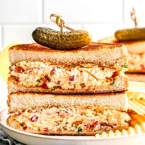 pimento cheese sandwich halves stacked on top of each other with a cornichon on top