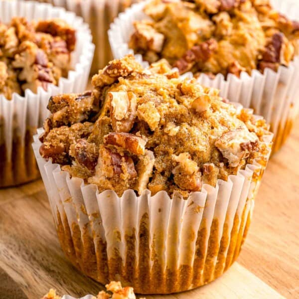 pumpkin pecan muffin in a white muffin liner with chopped pecans on top