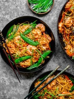 Overhead shot of shrimp chow mein served in bowls with chopsticks.