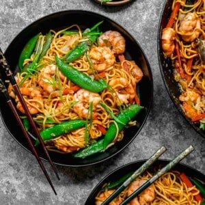 Overhead shot of shrimp chow mein served in bowls with chopsticks.