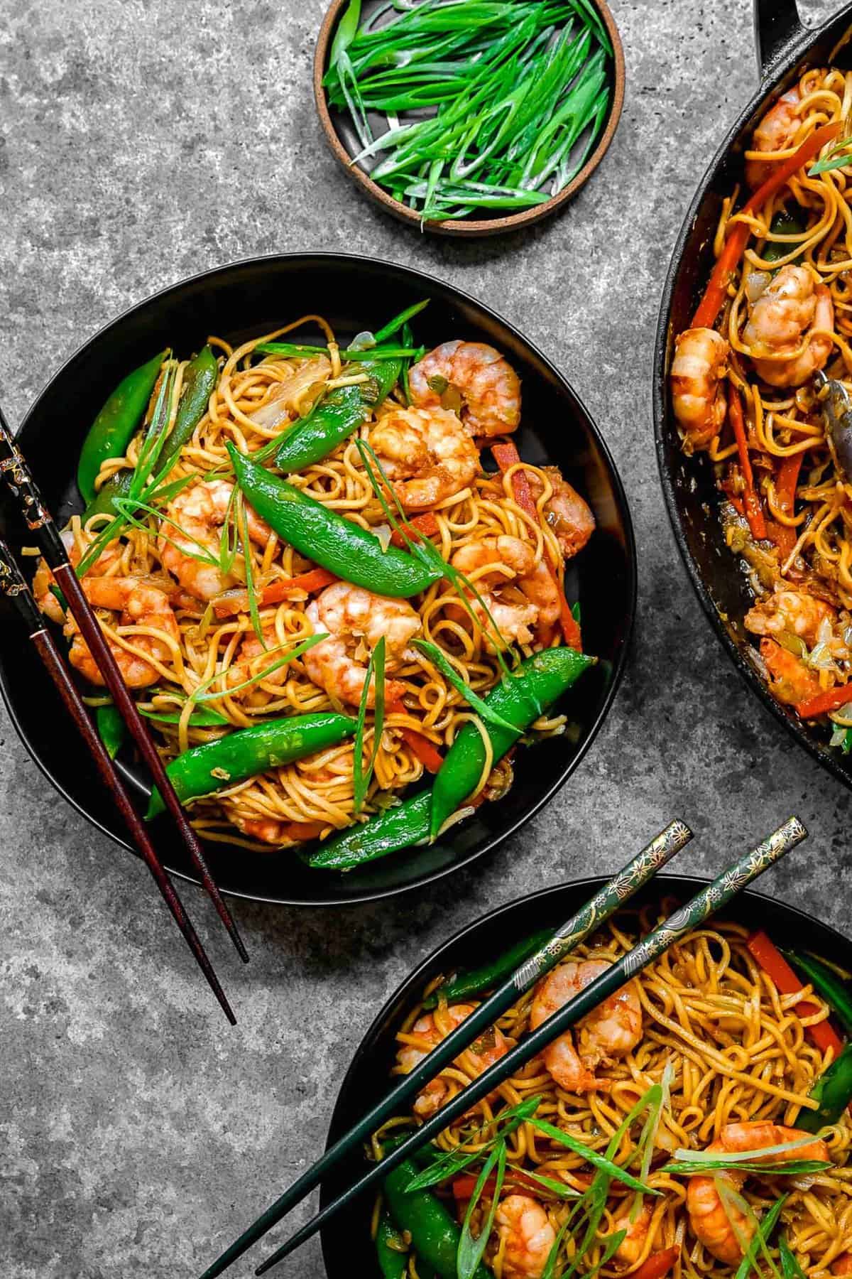 Overhead shot of shrimp chow mein served in bowls with chopsticks.