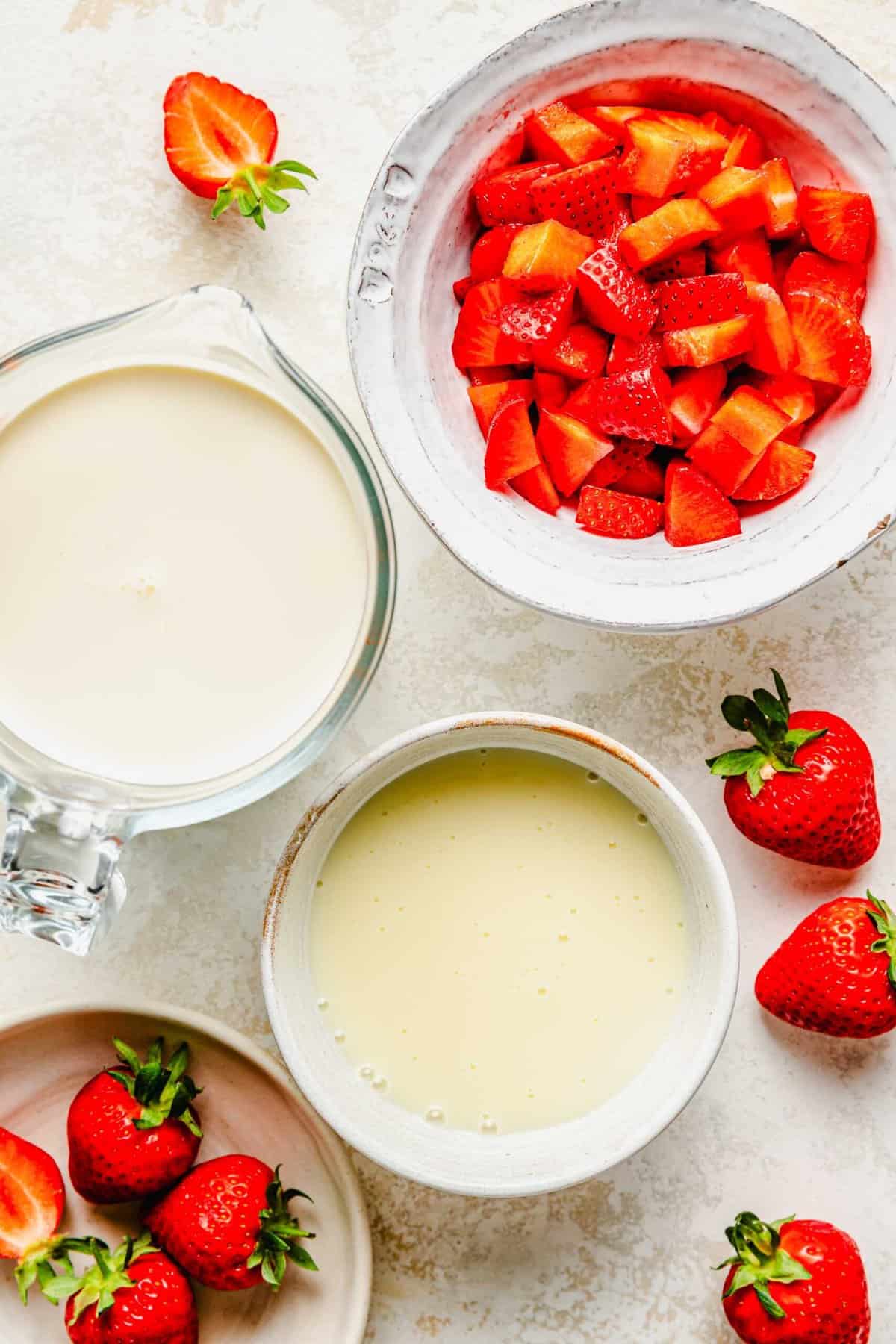 Ingredients for homemade strawberry ice cream separated into bowls.