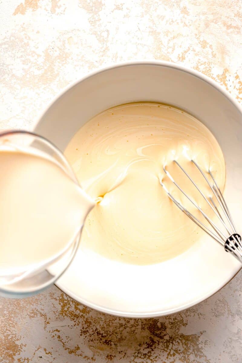 Whisking together heavy whipping cream and sweetened condensed milk.