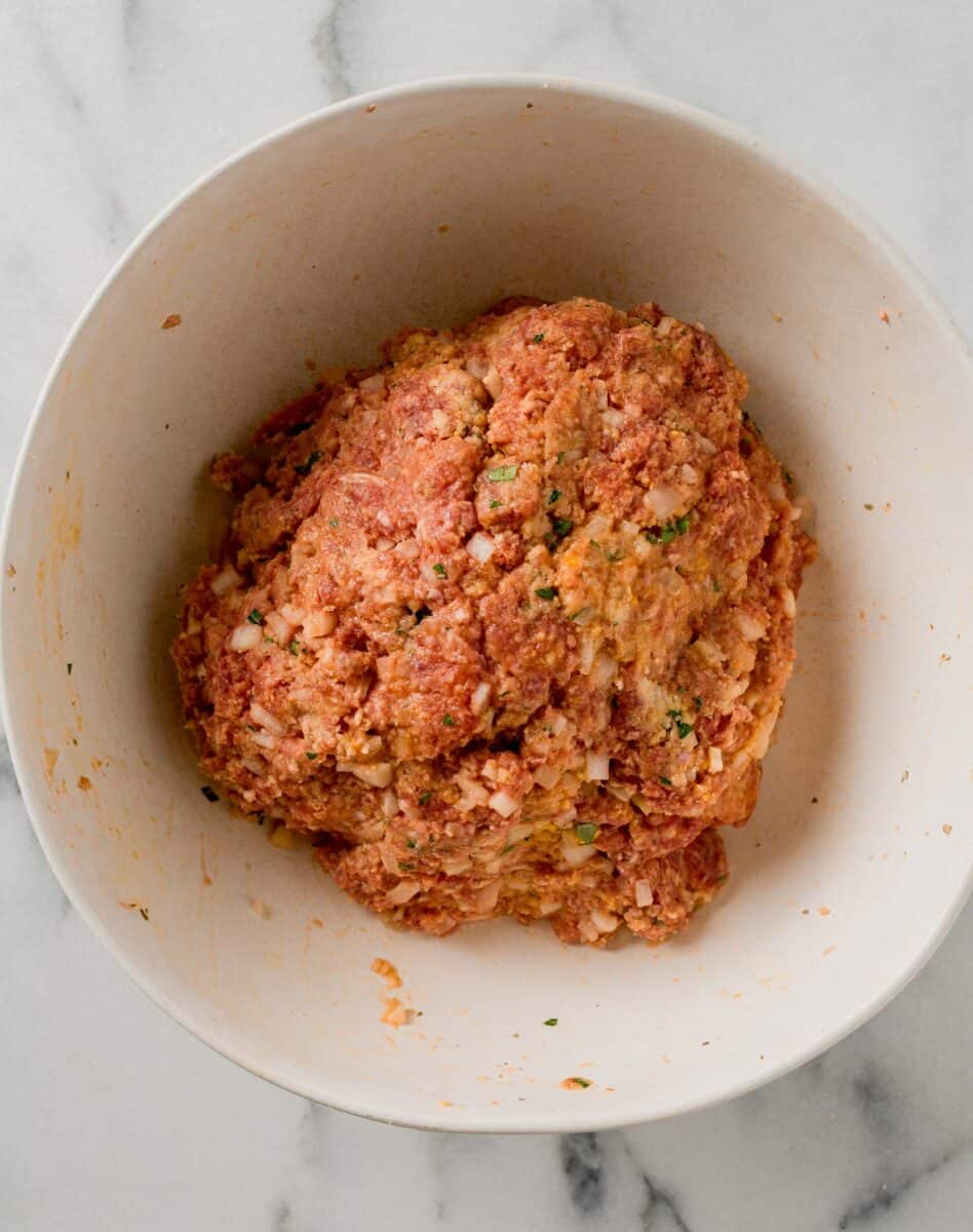 raw meatloaf mixture formed into a large ball in a white bowl