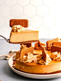 a slice of biscoff cheesecake is being lifted in the air with a metal cake spoon