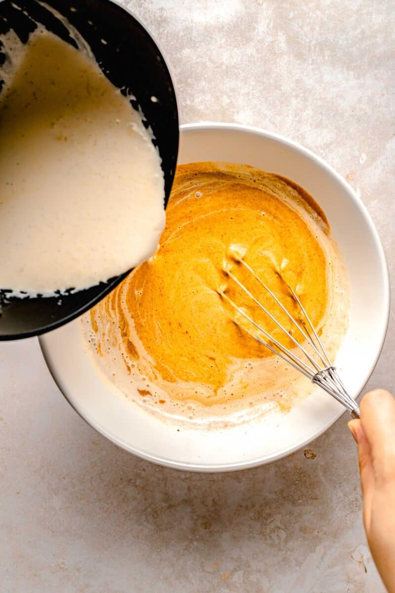 Whisking warm heavy cream into pumpkin custard base.