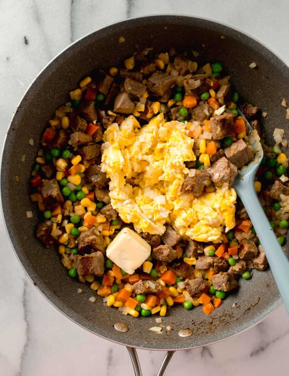 scrambled eggs and pad of butter added into the wok along with the vegetables and steak