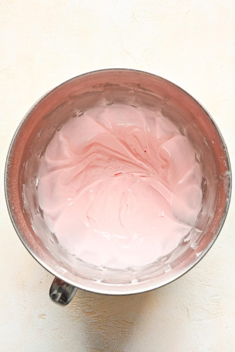 pink tinted cream cheese frosting in a metal stand mixer bowl