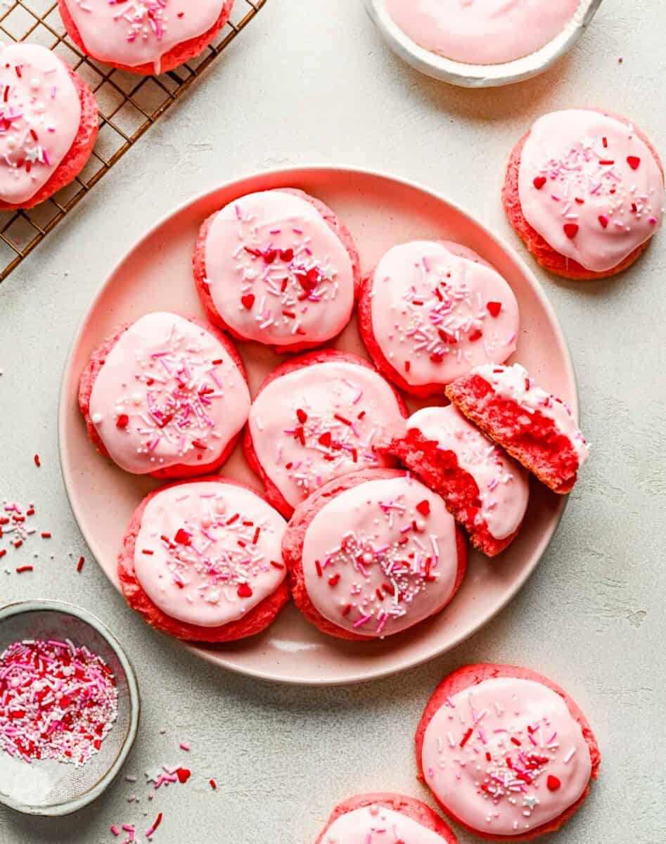 strawberry cream cheese cookies on a pink plate with cookies scattered around