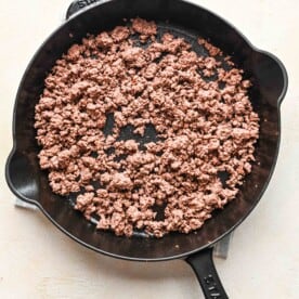 cooked ground beef cooked into smaller pieces in a cast iron skillet