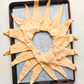 crescent dough triangles arranged on a baking sheet with parchment paper in a ring
