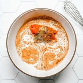 pumpkin alfredo pasta mixture in a white bowl with a whisk