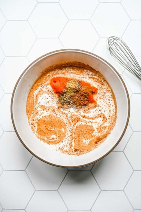 pumpkin alfredo pasta mixture in a white bowl with a whisk
