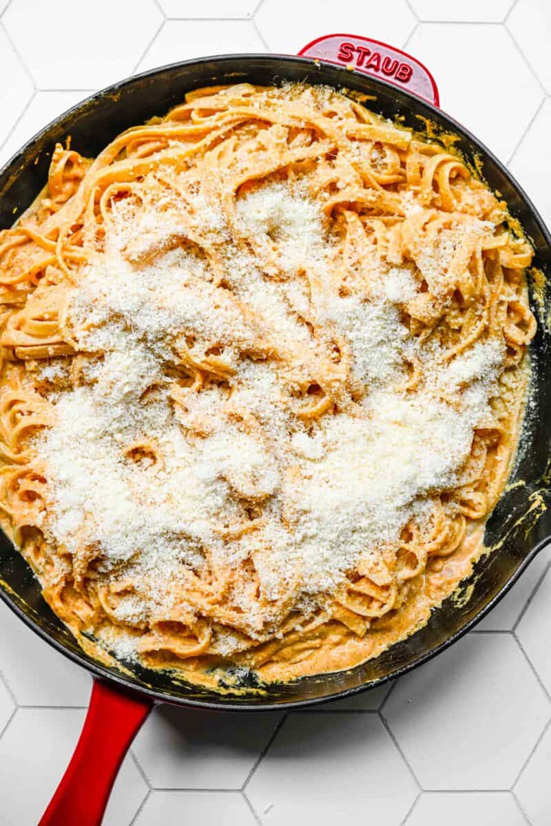 parmesan cheese sprinkled on top of the pasta in the cast iron skillet