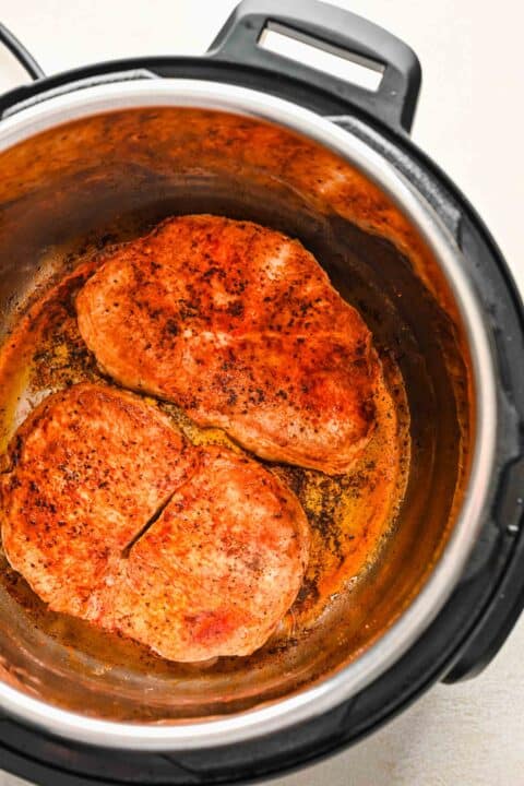 seared pork chops in the insert of the instant pot