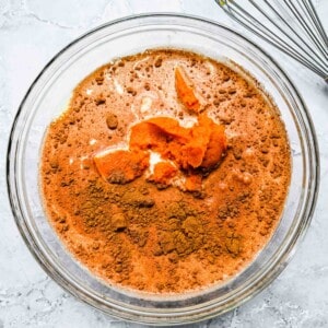 pumpkin puree and cinnamon spices can be seen in a clear bowl with milk and heavy cream