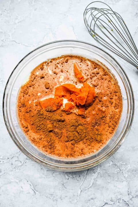 pumpkin puree and cinnamon spices can be seen in a clear bowl with milk and heavy cream