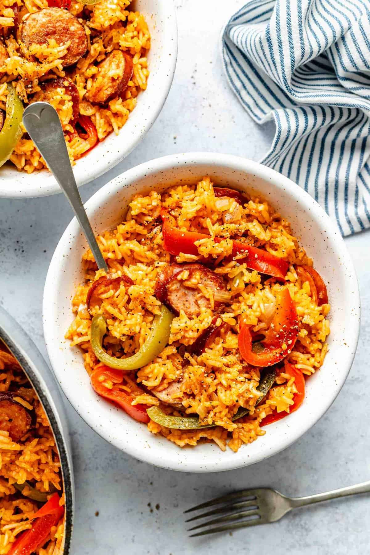 Overhead of smoked sausage and rice in a bowl with a fork.