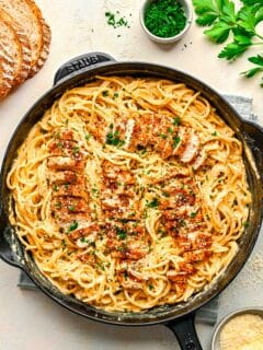 cajun chicken alfredo pasta in cast iron skillet with fresh parsley sprinkled on top