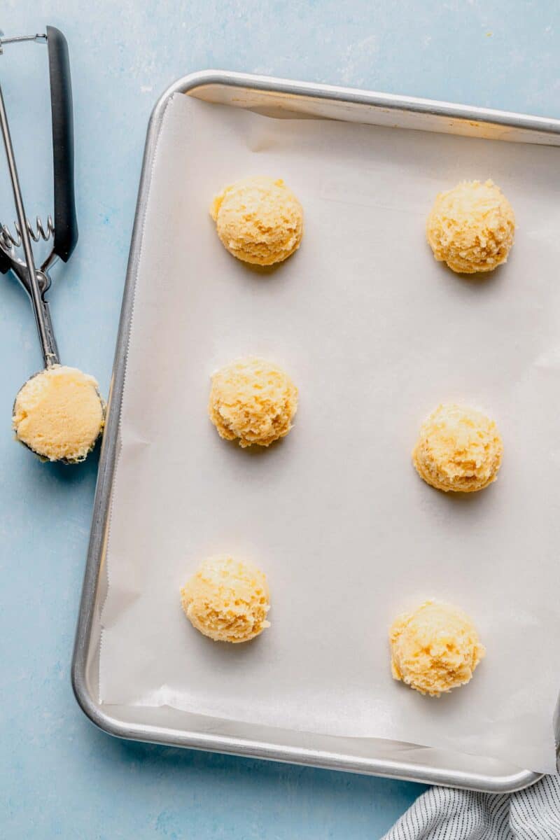 Scooping lemon cookie dough into cookies.