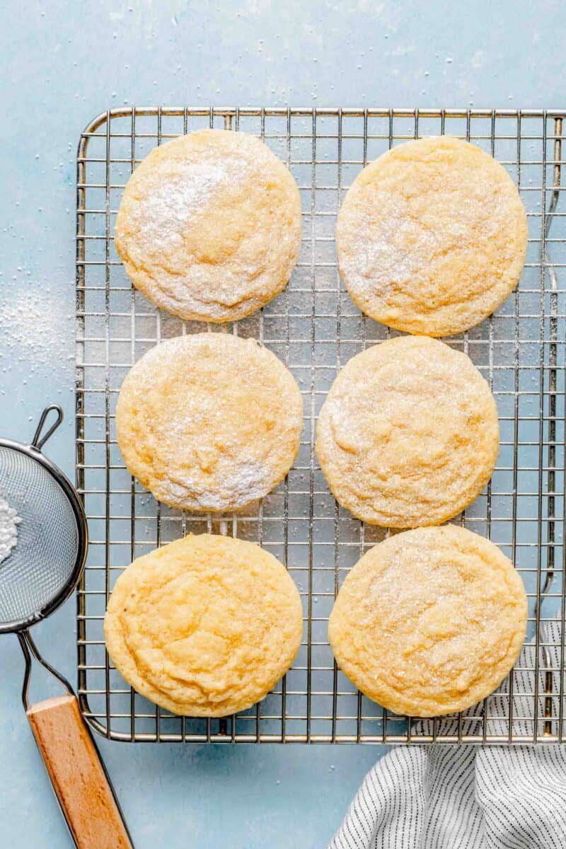 Lemon cookies on a cooling rack dusted with powdered sugar.