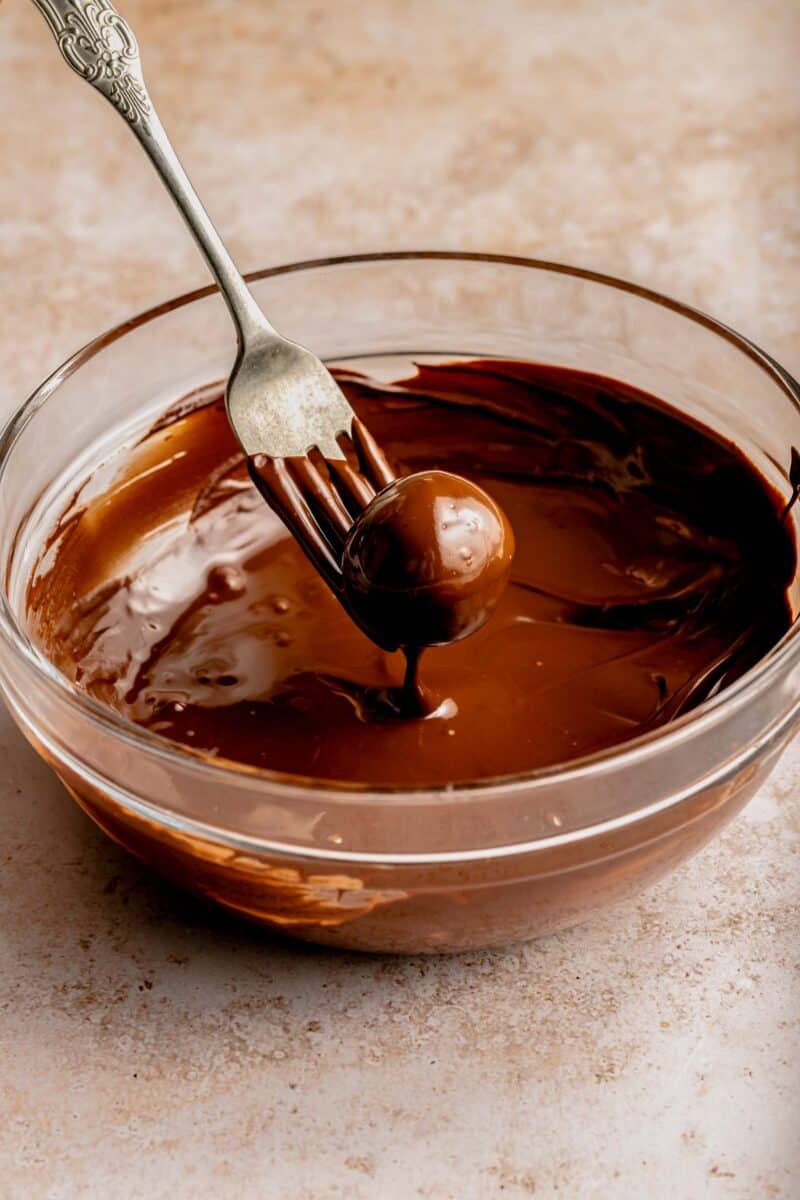 Dipping a peanut butter ball into chocolate with a fork.