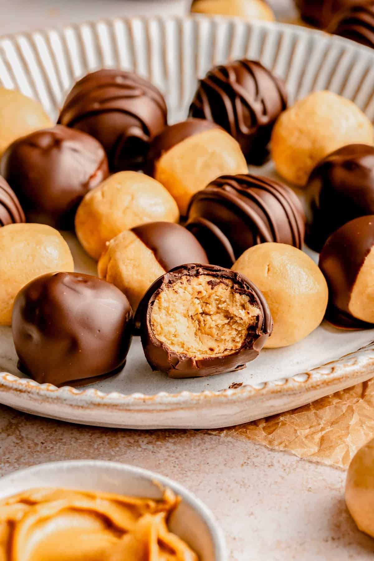 Peanut butter balls on a plate. One has a bite taken out of it.