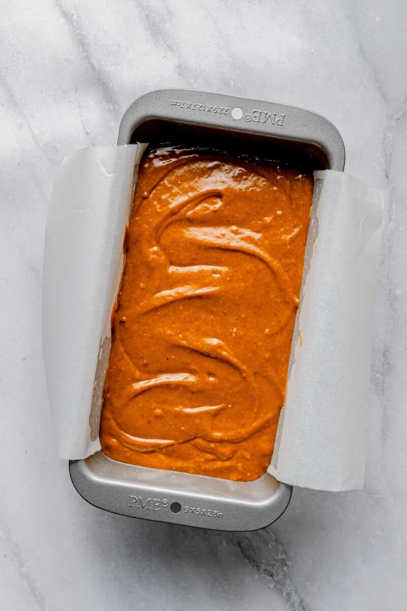 Sweet potato bread batter in a loaf pan lined with parchment paper.