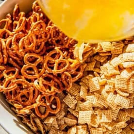 butter mixture being poured on top of chex cereal and pretzels