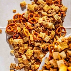 homemade chex mix being poured out onto parchment paper