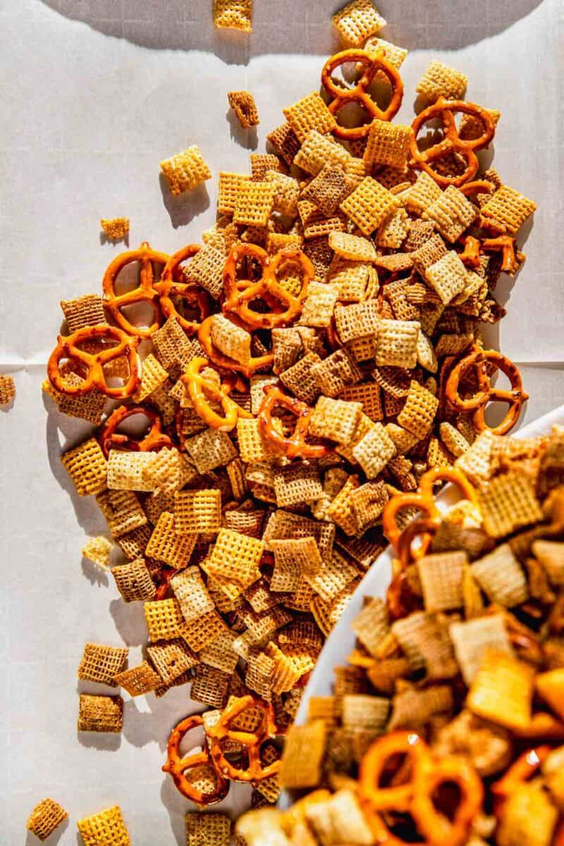 homemade chex mix being poured out onto parchment paper