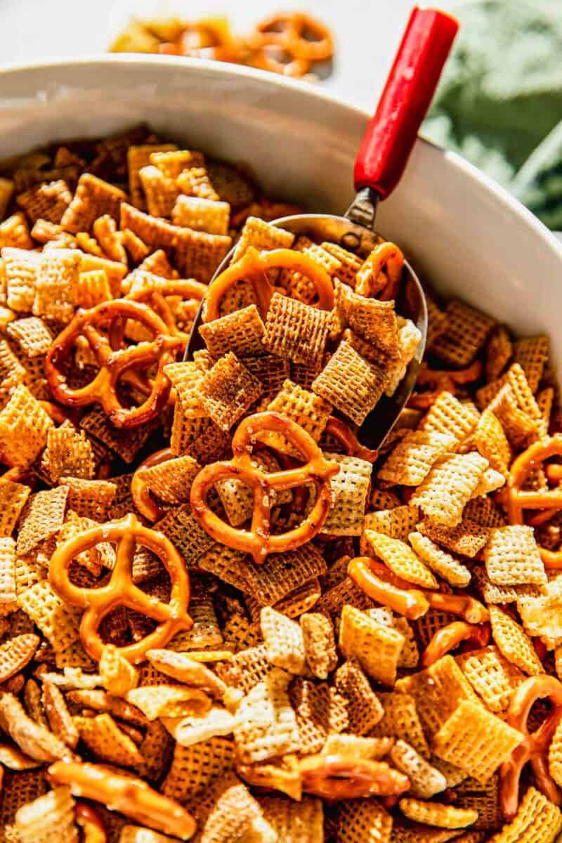 chex mix mixture on a metal, red-handled scoop in a large bowl