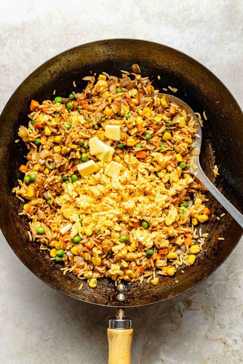 Stirring cooked eggs and butter into fried rice.