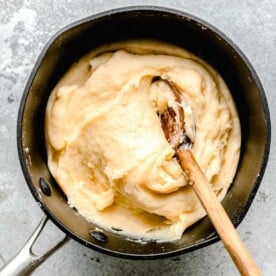 churro dough in a nonstick pot with a wooden spoon