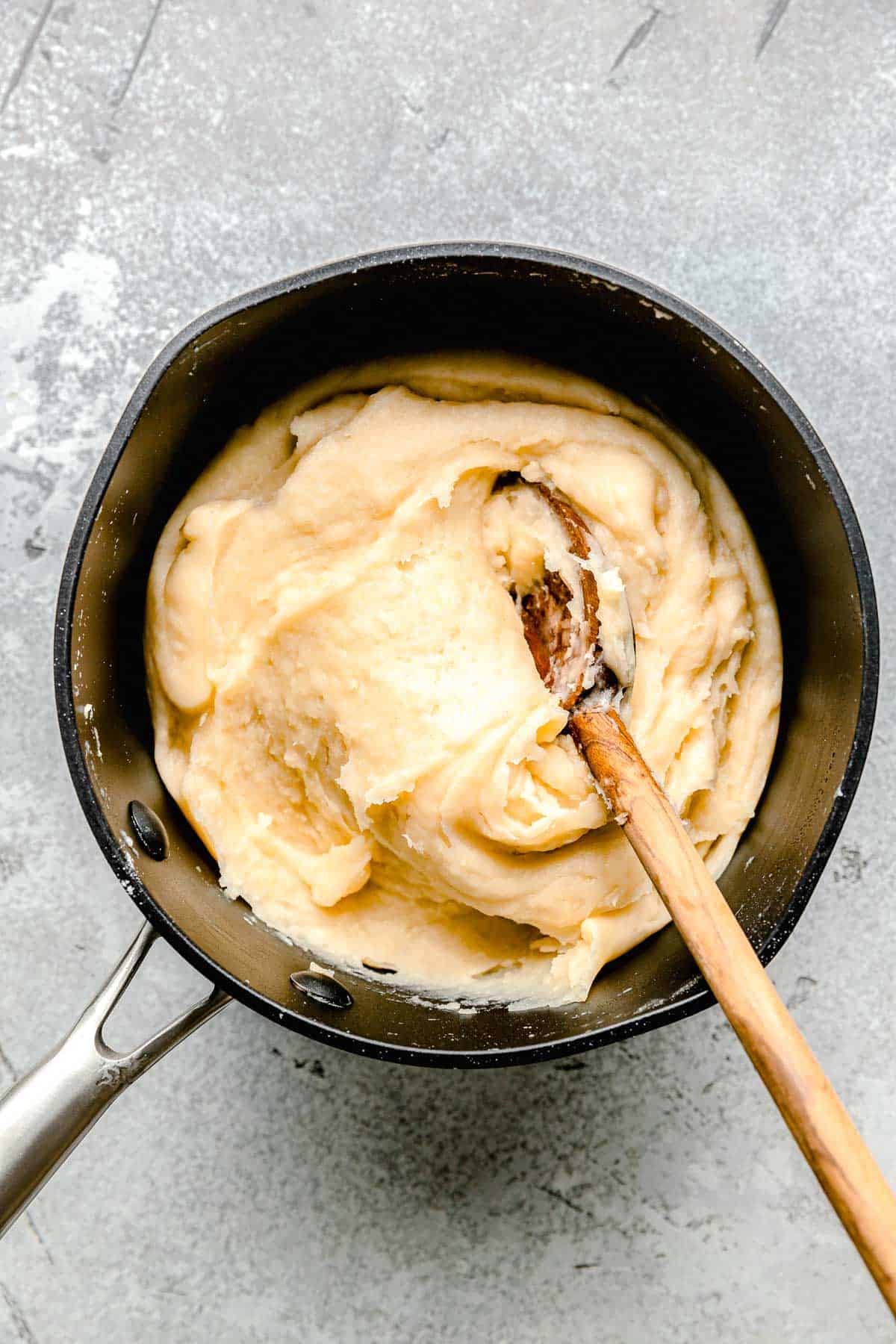 churro dough in a nonstick pot with a wooden spoon