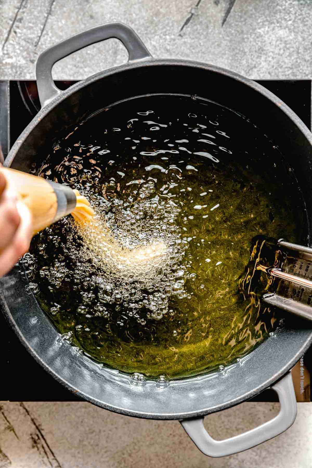 piping churro dough into frying oil on the stovetop