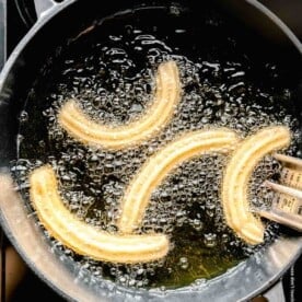 fried churro dough in a cast iron pot with hot oil