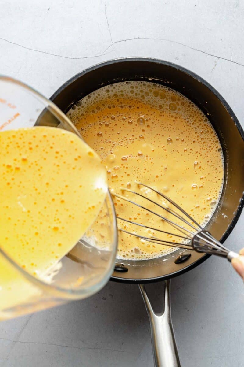 Whisking tempered egg yolks into custard for ice cream.
