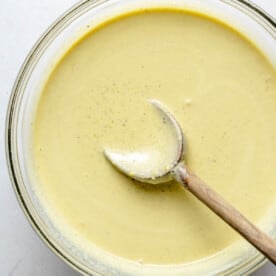 Pistachio ice cream base in a bowl with a wooden spoon.