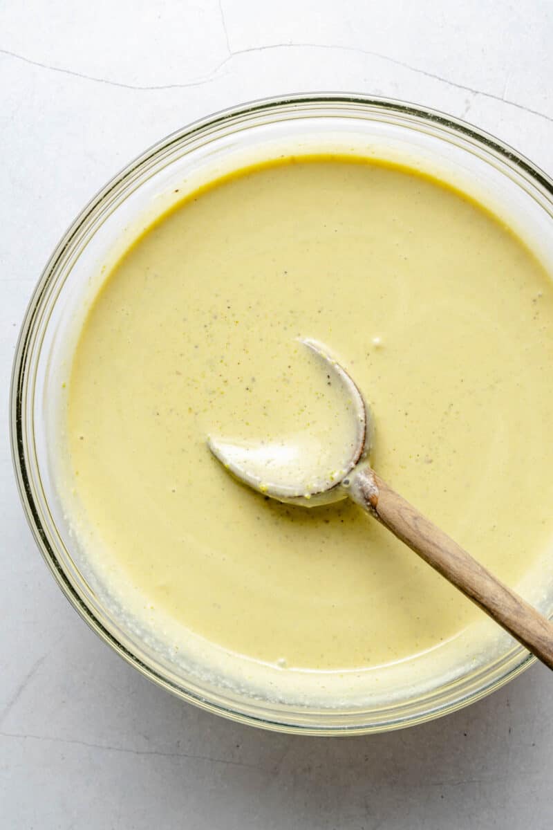 Pistachio ice cream base in a bowl with a wooden spoon.