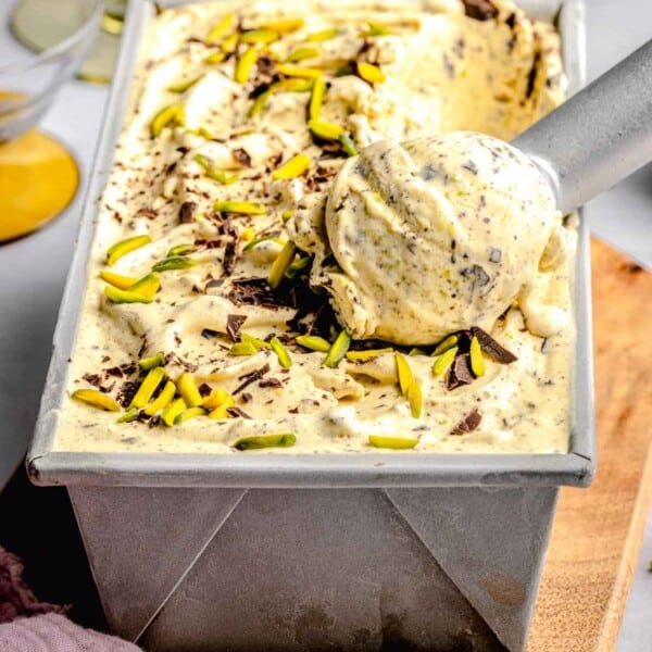 Scooping pistachio ice cream out of a loaf pan.