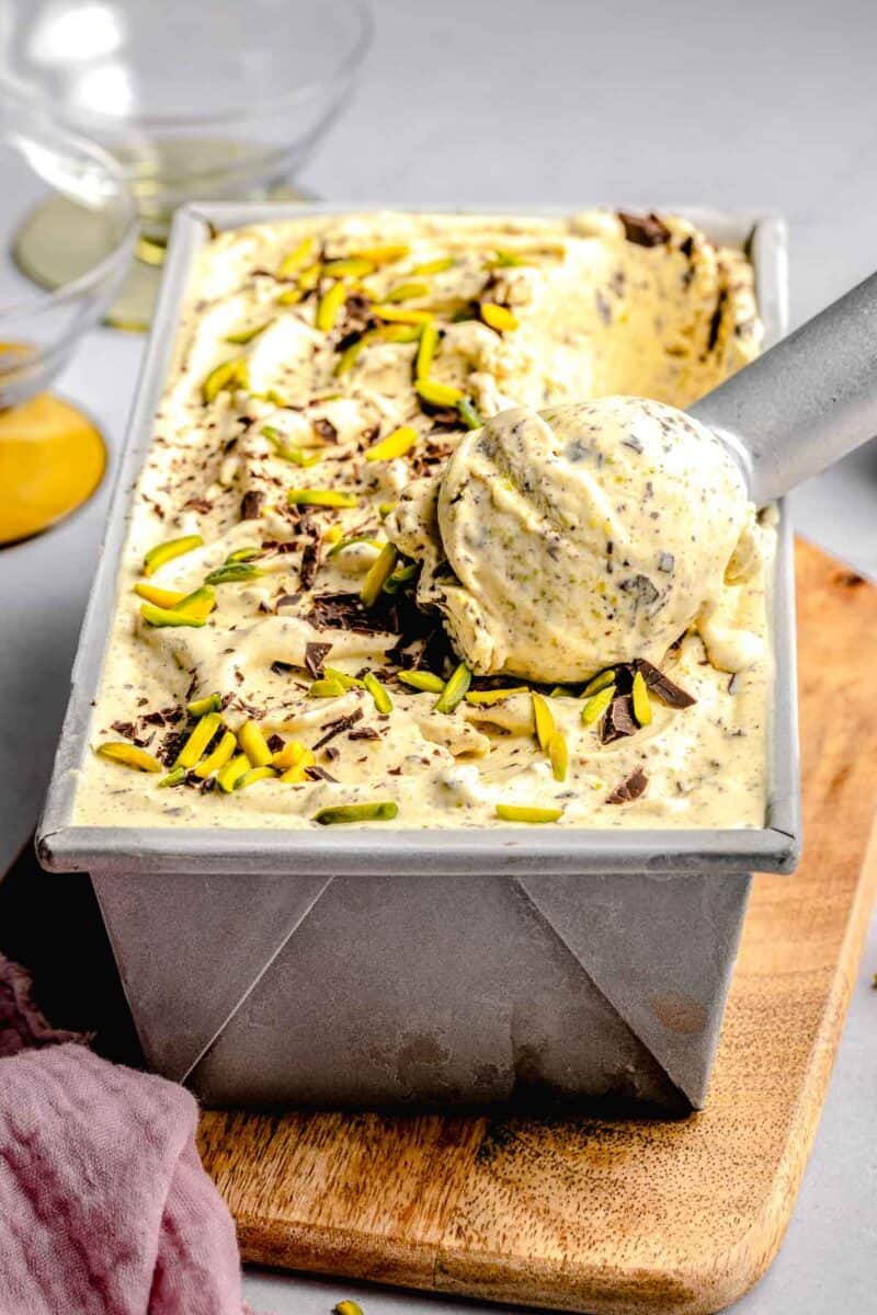 Scooping pistachio ice cream out of a loaf pan.