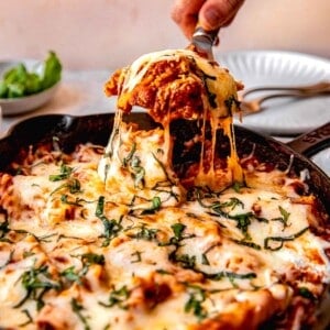 Scooping a serving of skillet lasagna out of the pan.