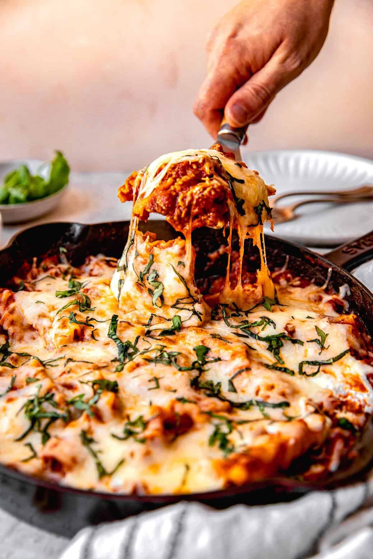 Scooping a serving of skillet lasagna out of the pan.