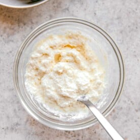 Whisking together ricotta and grated parmesan cheese.