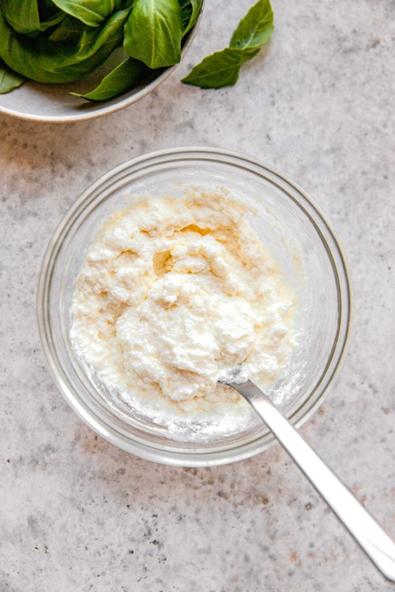 Whisking together ricotta and grated parmesan cheese.