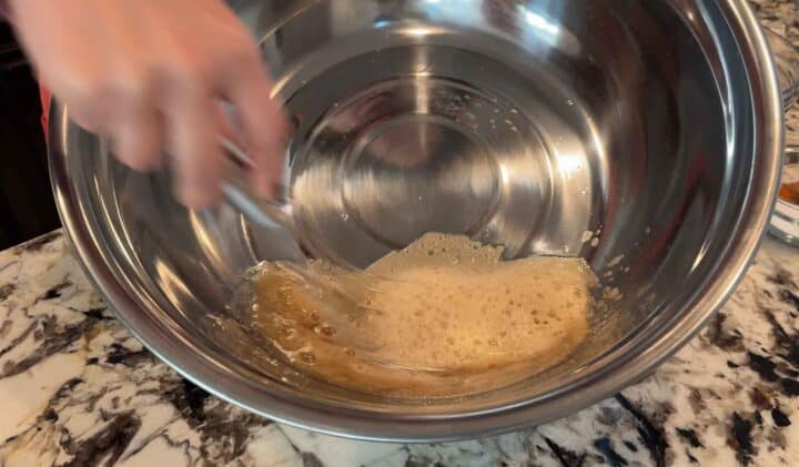 whisking egg white and maple syrup in a large metal bowl