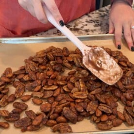 spreading spiced nuts into an even layer on a metal baking sheet