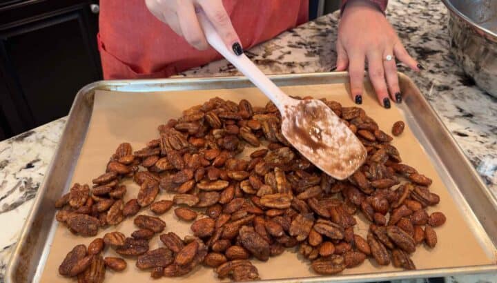 spreading spiced nuts into an even layer on a metal baking sheet
